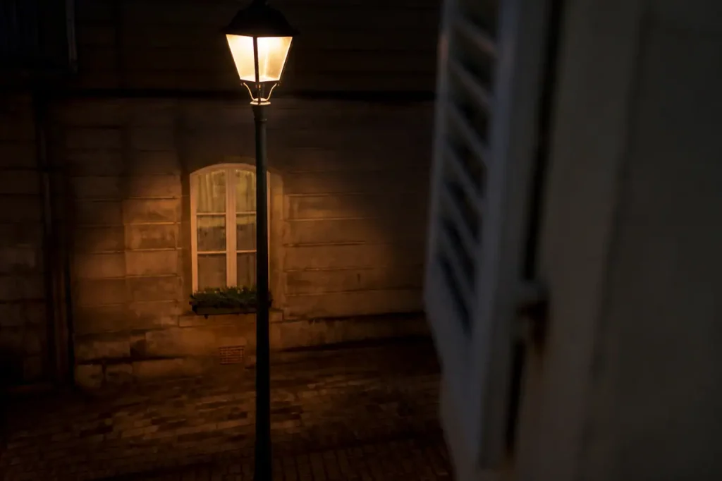 Lampadaire de rue eclairant une fenetre dans la nuit