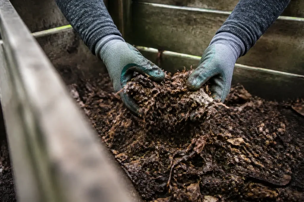 Mains gantees melangent compost brun au fond fosse