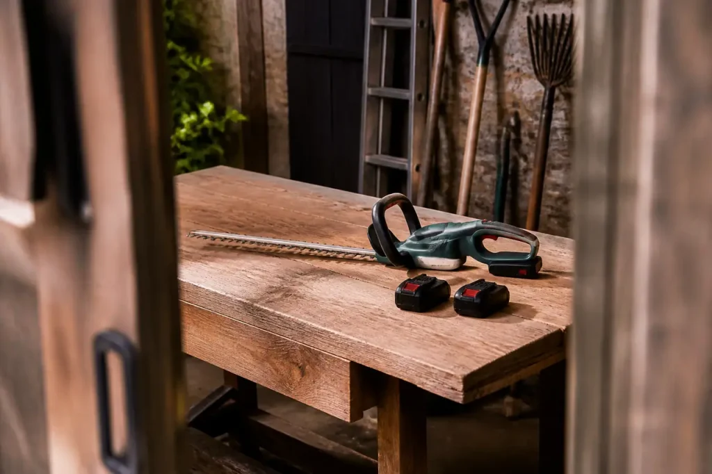 Taille-haie sans fil sur une table, deux batteries